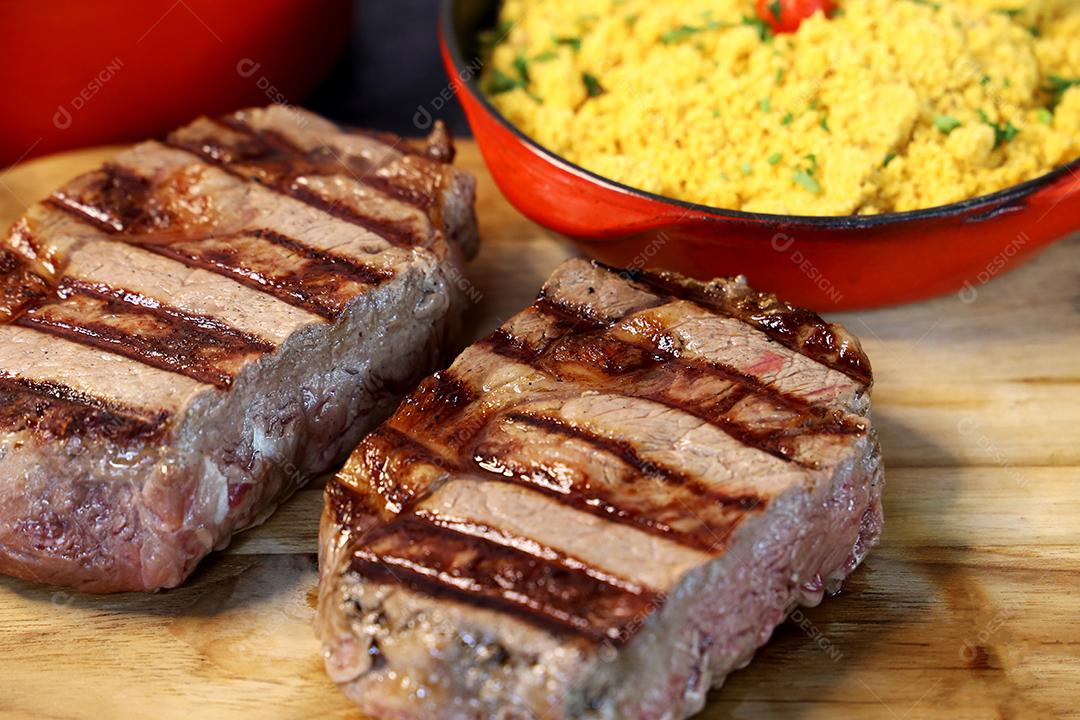 Delicioso bife ancho suculento com marcas de grelha e acompanhamento de farofa ao lado. Comida brasileira. Vista superior JPG