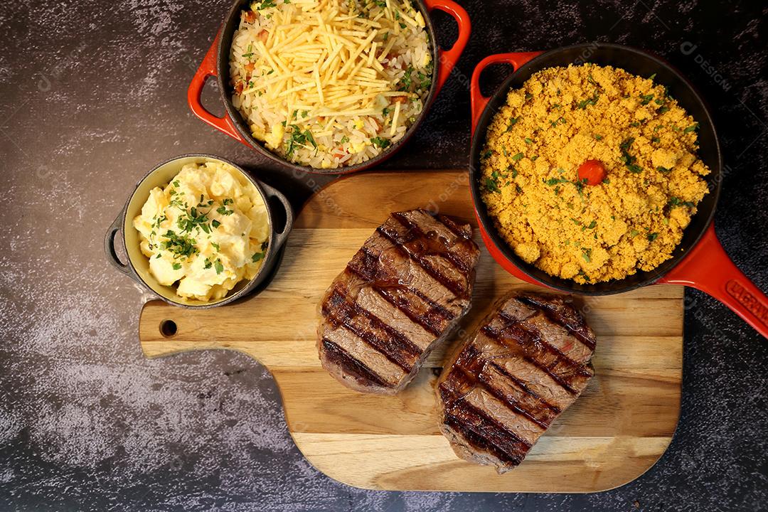 Delicioso bife ancho suculento com marcas de grelha e acompanhamento de farofa ao lado. Comida brasileira. Vista superior JPG