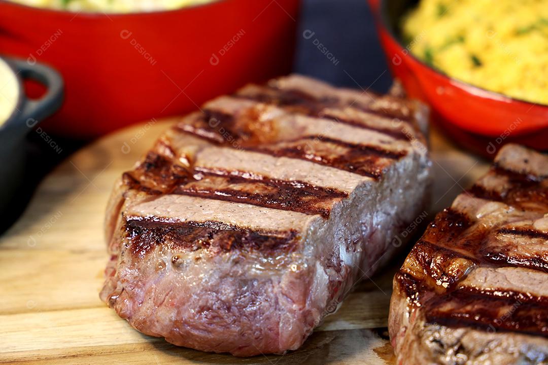 Delicioso bife ancho suculento com marcas de grelha e acompanhamento de farofa ao lado. Comida brasileira. Vista superior JPG