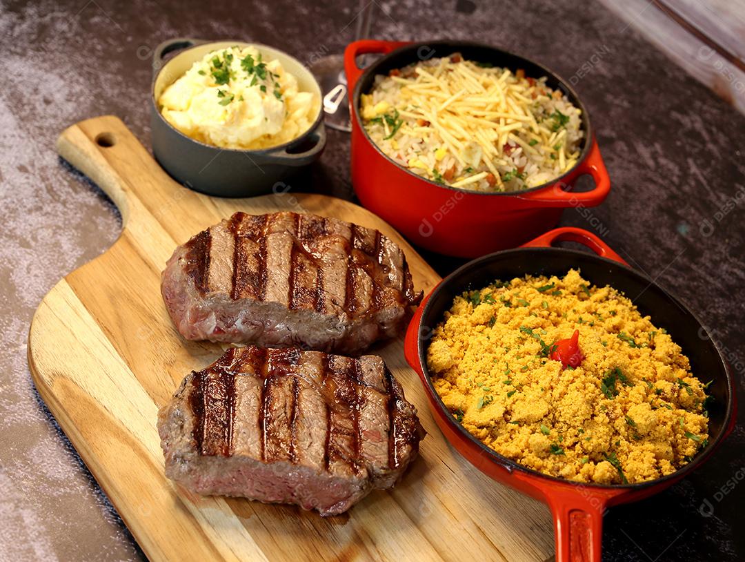 Delicioso bife ancho suculento com marcas de grelha e acompanhamento de farofa ao lado. Comida brasileira. Vista superior JPG