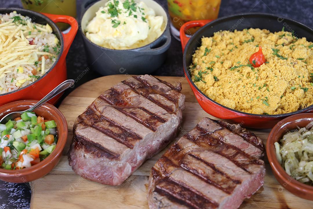 Bife de ancho com marcas de churrasqueira e acompanhamento de farofa ao lado. Comida brasileira JPG