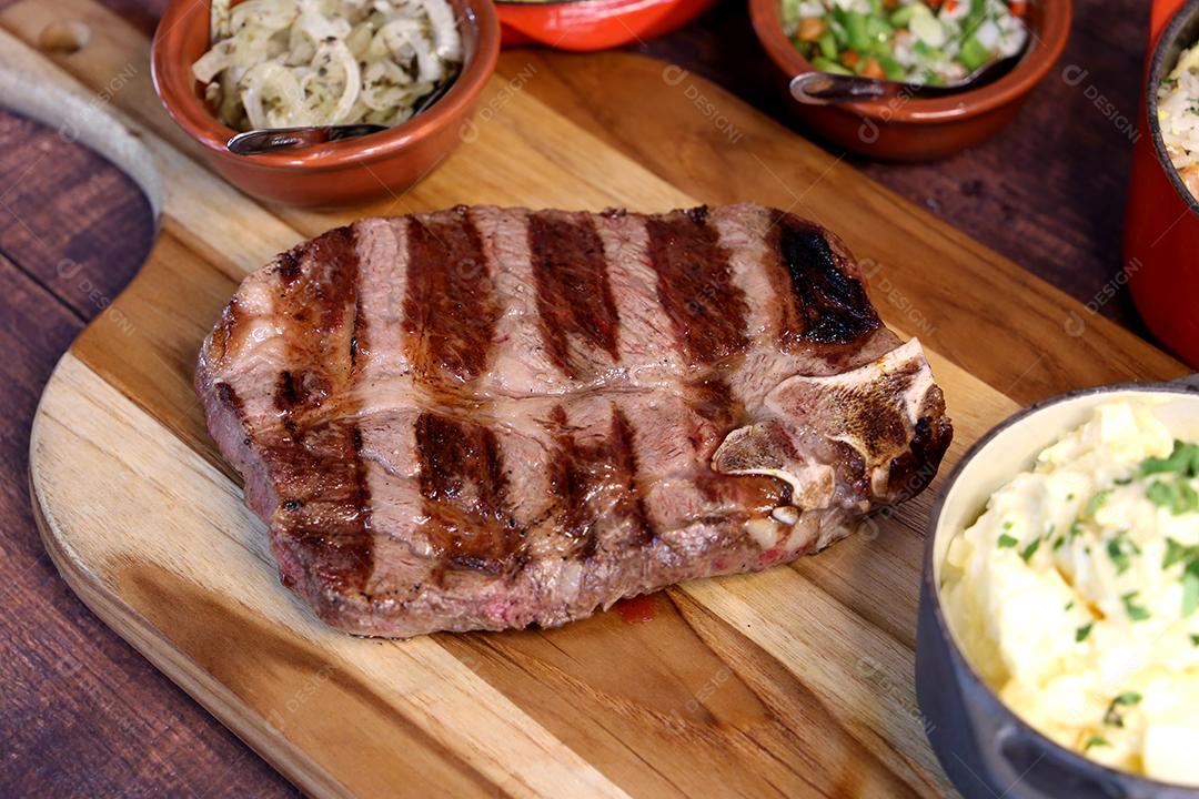 Costela curta ou Rib Premium. Bife grelhado em Parrilla argentina com marcas de grelha em uma tábua de madeira ao fundo. Comida brasileira JPG