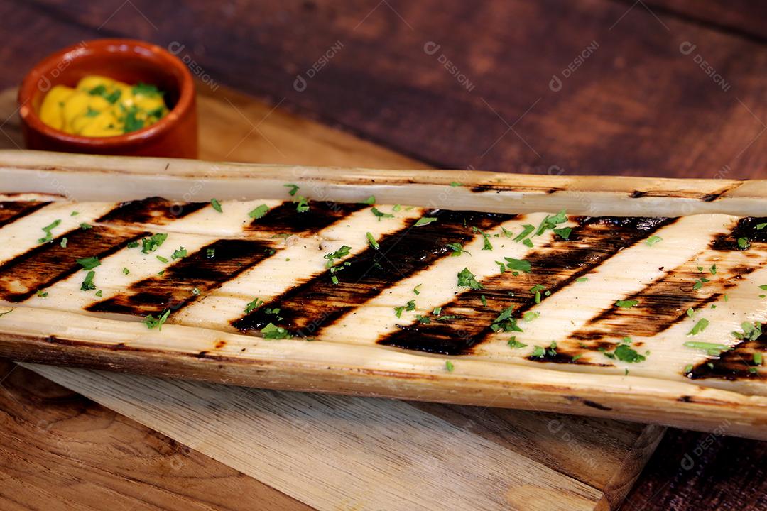 Lindos corações inteiros de palma com marcas de churrasco em uma tábua de madeira com uma faca ao lado e molho de mostarda JPG