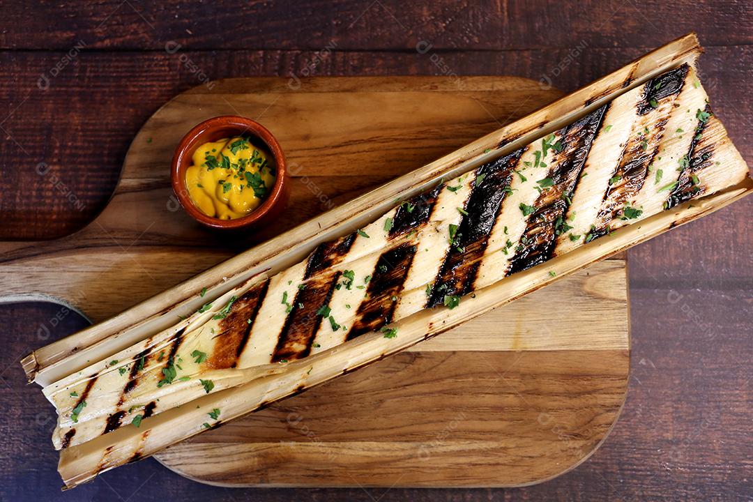 Lindos corações inteiros de palma com marcas de churrasco em uma tábua de madeira com uma faca ao lado e molho de mostarda JPG