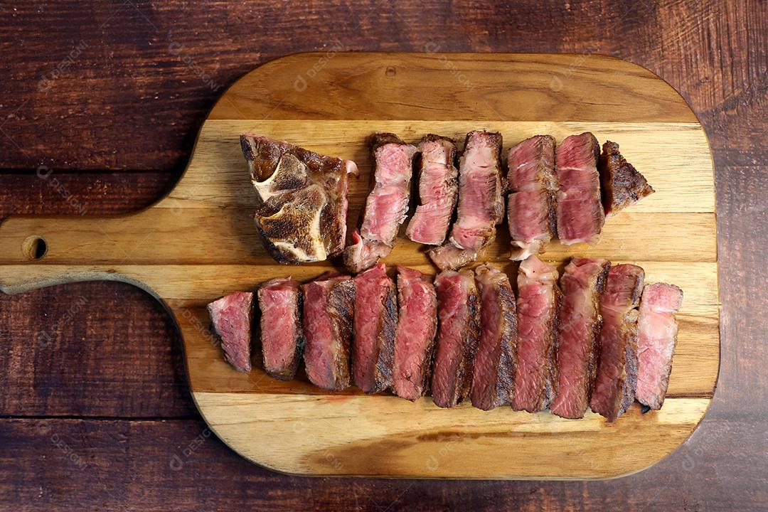 Costela Curta ou Costela Premium fatiado em uma tábua de madeira. Bife raro fatiado JPG