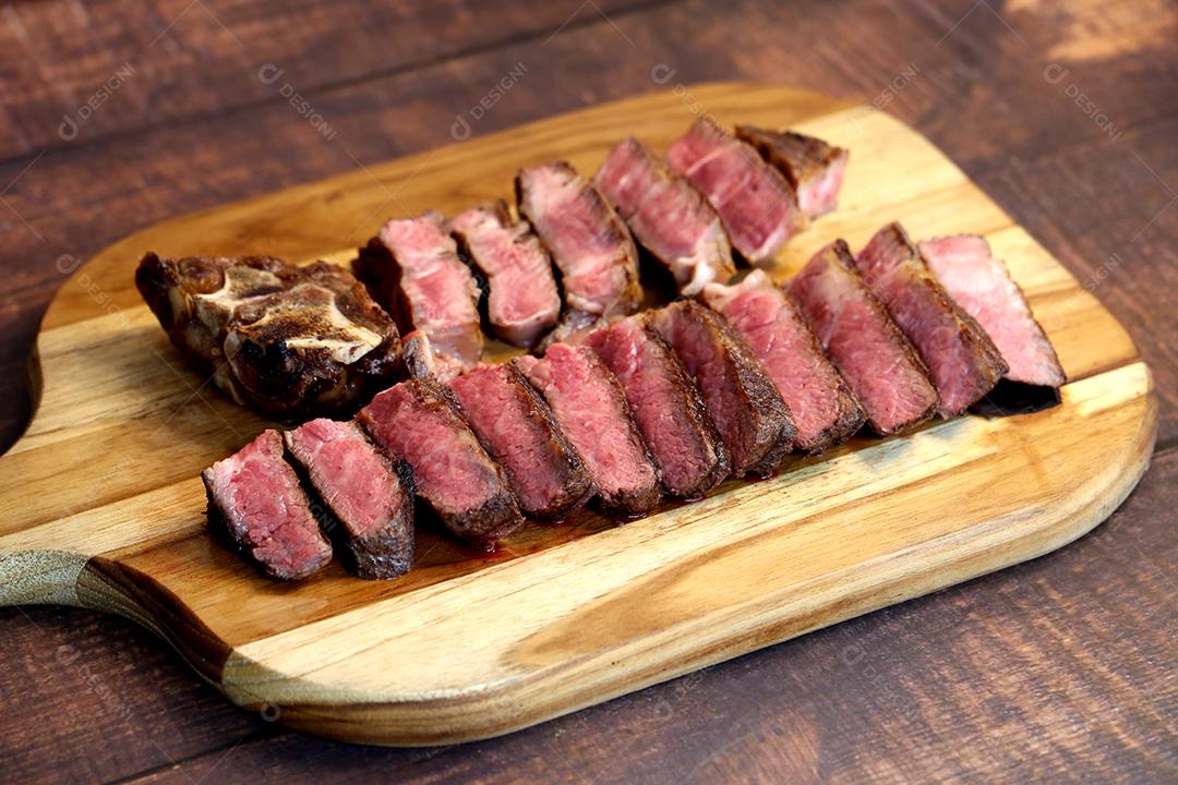 Costela Curta ou Costela Premium fatiado em uma tábua de madeira. Bife raro fatiado JPG