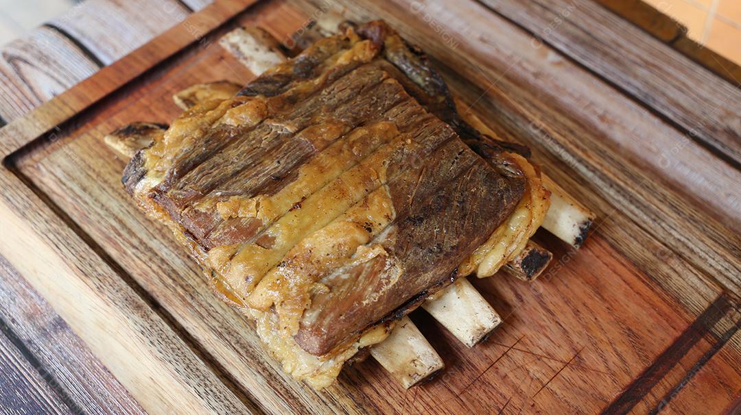 Costela, costela. Deliciosa costela assada com ossos grandes. Servido em uma tábua de madeira JPG