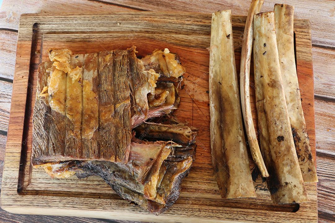 Costela, costela. Deliciosa costela assada com ossos grandes. Servido em uma tábua de madeira JPG