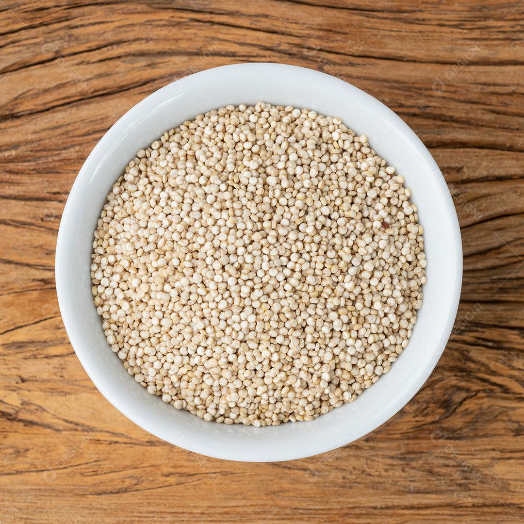 Grãos de quinoa crus em uma tigela sobre mesa de madeira JPG