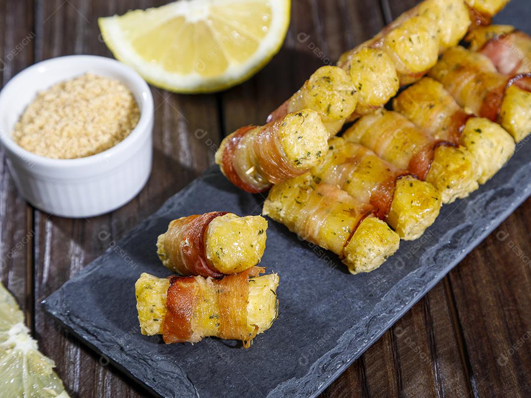 Espetinhos de mandioca enrolados no bacon medalhão de mandioca Imagem JPG