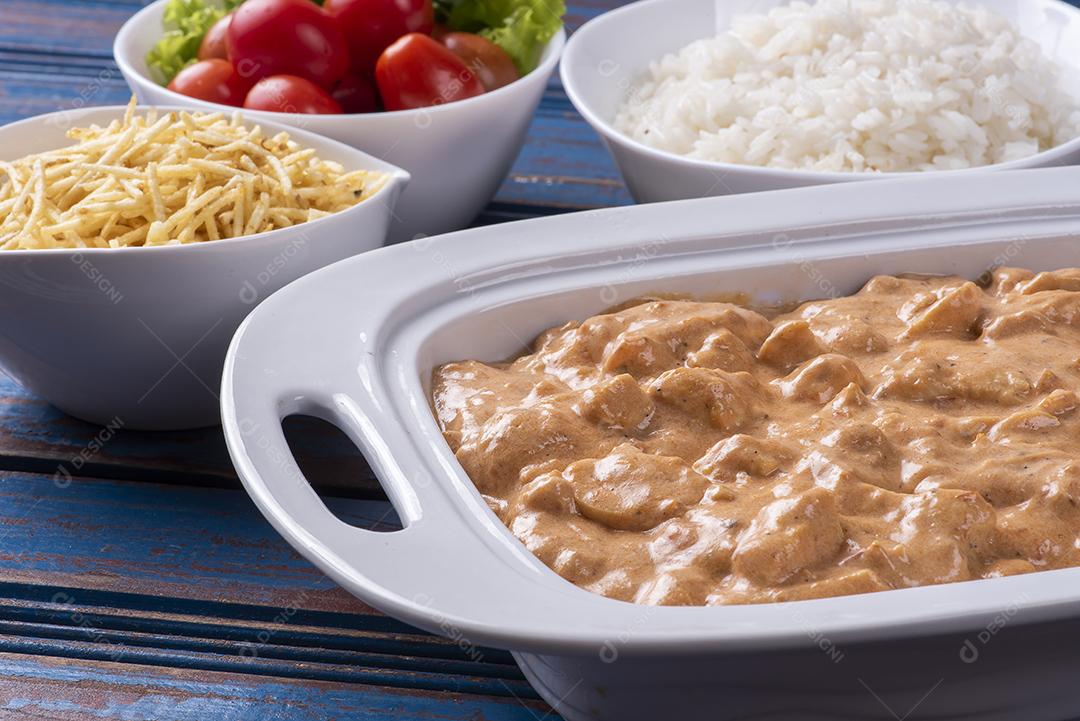 Estrogonofe de frango acompanhado de arroz, salada e palha de batata JPG