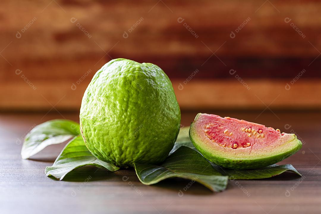 Faca de aço antiga e goiabas vermelhas fatiadas em fundo de madeira rústico Imagem JPG