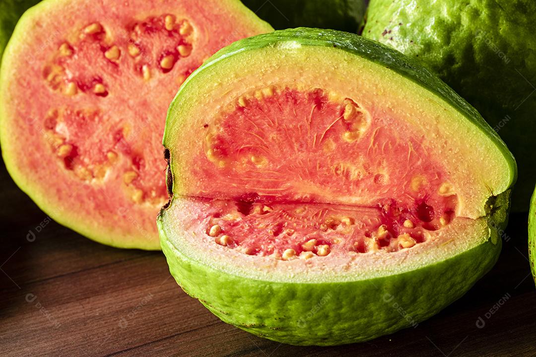 Faca de aço antiga e goiabas vermelhas fatiadas em fundo de madeira rústico Imagem JPG