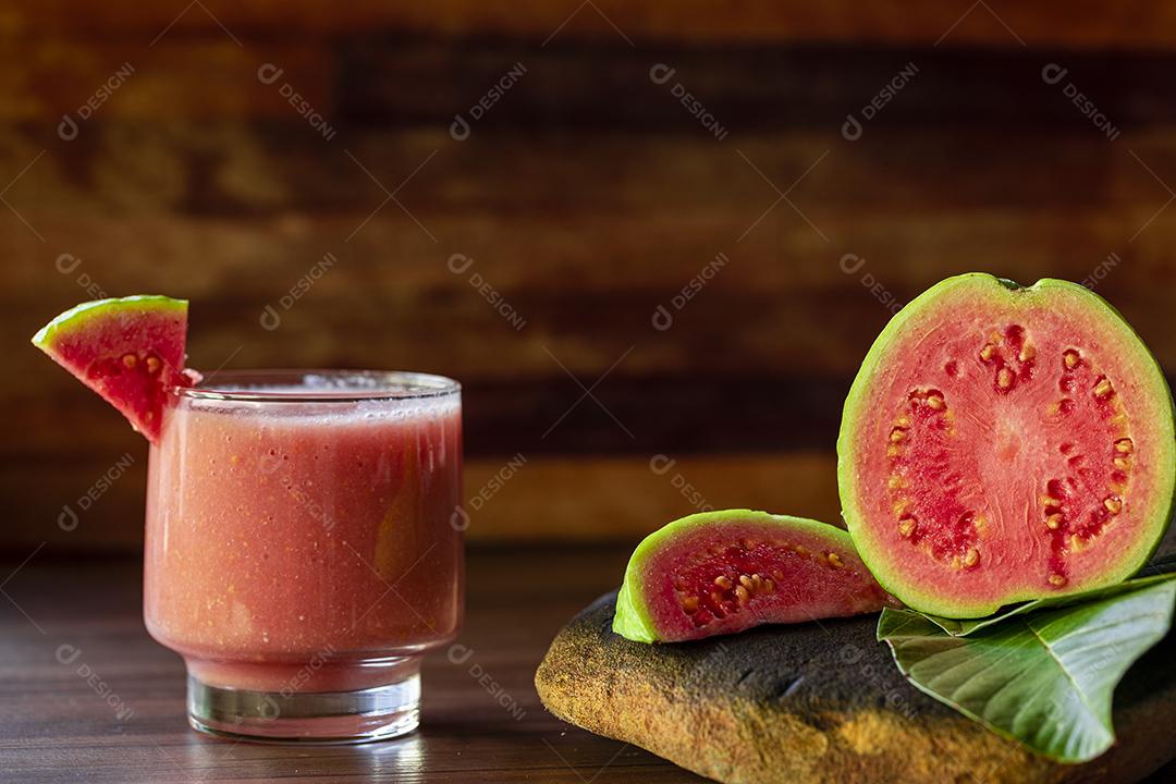 Delicioso suco de goiaba vermelha ao lado de uma fatia de goiaba folhas Imagem JPG