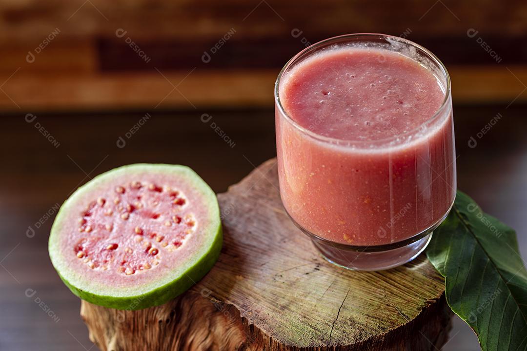 Delicious red guava juice next to a slice of guava leaves Image JPG