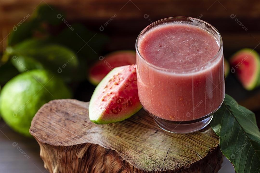 Delicioso suco de goiaba vermelha ao lado de uma fatia de goiaba folhas Imagem JPG