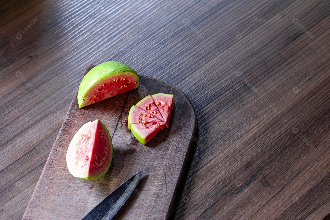 Goiabas vermelhas fatiadas em fundo de madeira rústico Imagem JPG