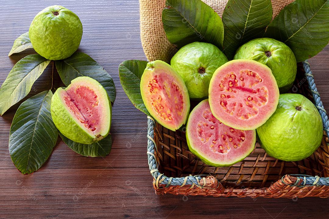 Goiabas vermelhas fatiadas em fundo de madeira rústico Imagem JPG