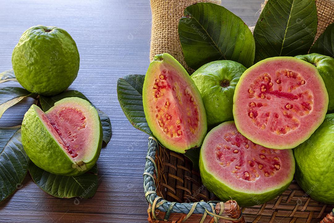 Goiabas vermelhas fatiadas em fundo de madeira rústico Imagem JPG