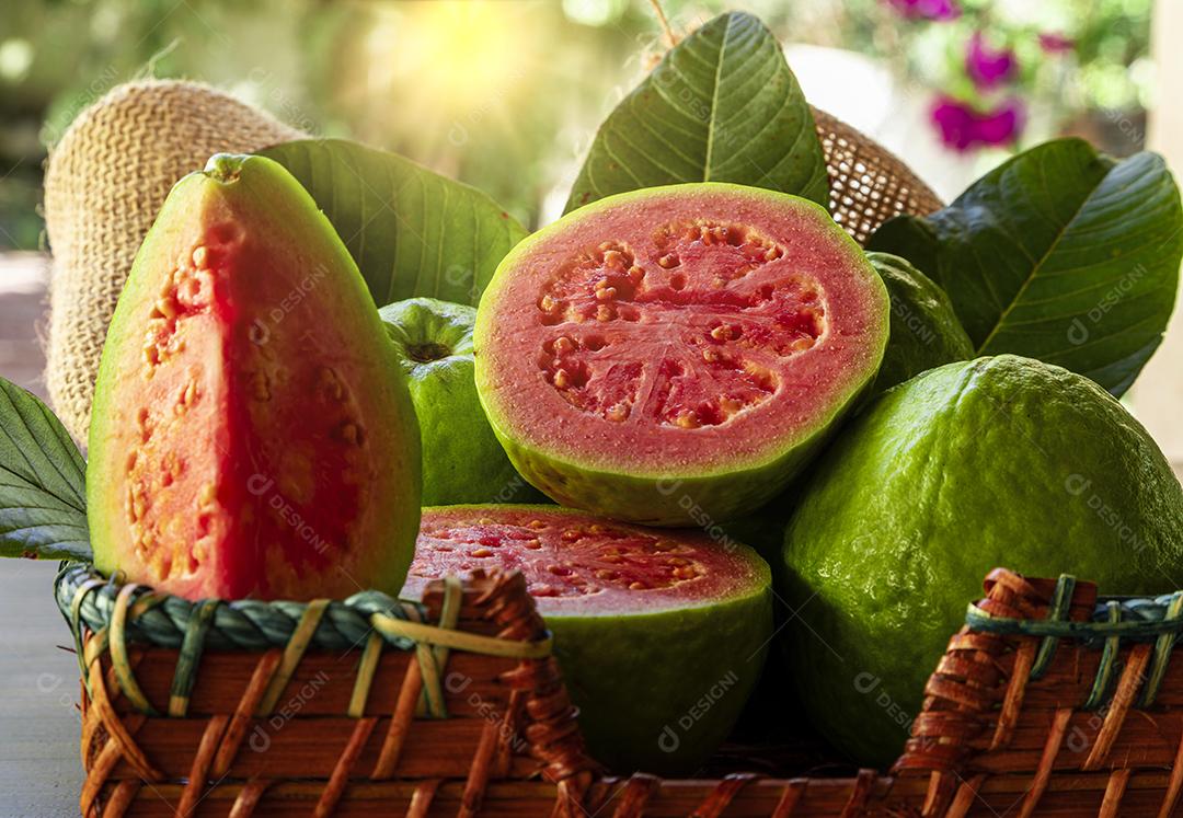 Goiabas vermelhas fatiadas em fundo de madeira rústico Imagem JPG