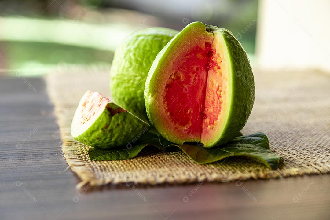 Goiabas vermelhas fatiadas em fundo de madeira rústico Imagem JPG