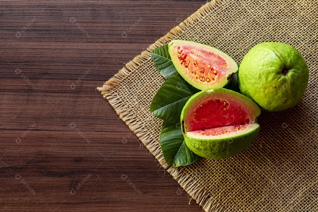 Goiabas vermelhas fatiadas em fundo de madeira rústico Imagem JPG