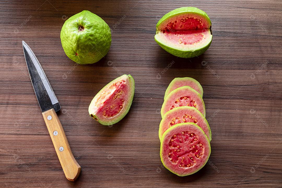 Goiabas vermelhas fatiadas em fundo de madeira rústico Imagem JPG