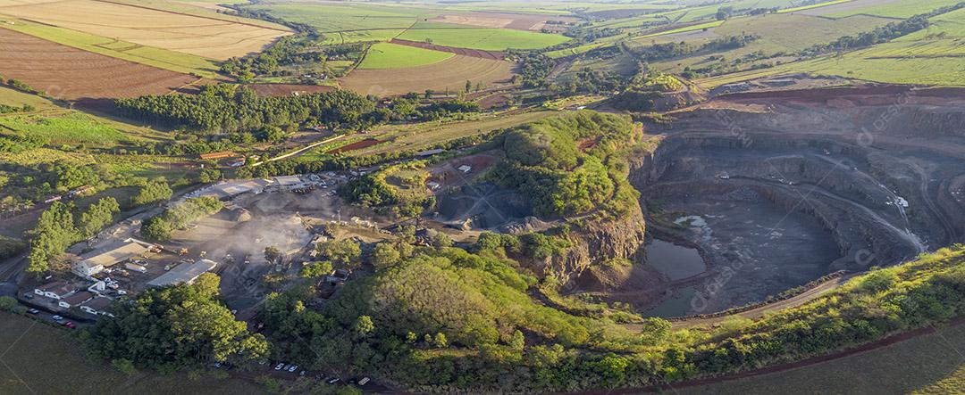 Tratores e caminhões removendo pedras de dentro de um buraco de pedreira Imagem JPG