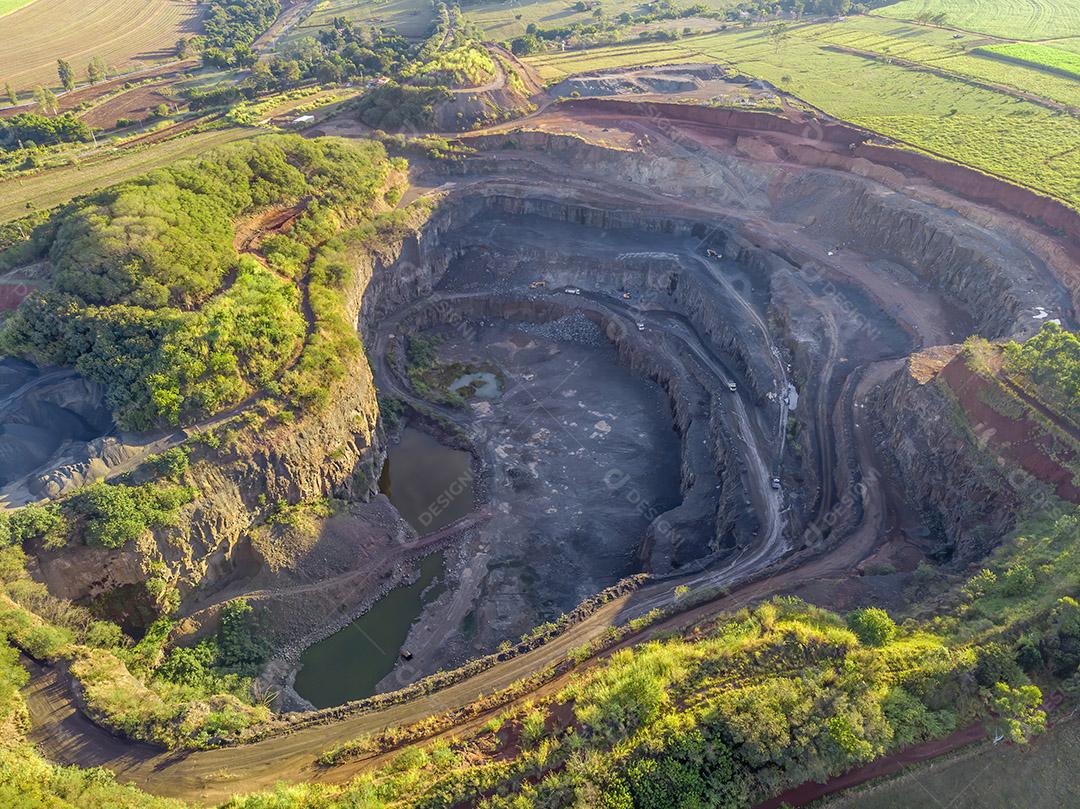 Tratores e caminhões removendo pedras de dentro de um buraco de pedreira Imagem JPG