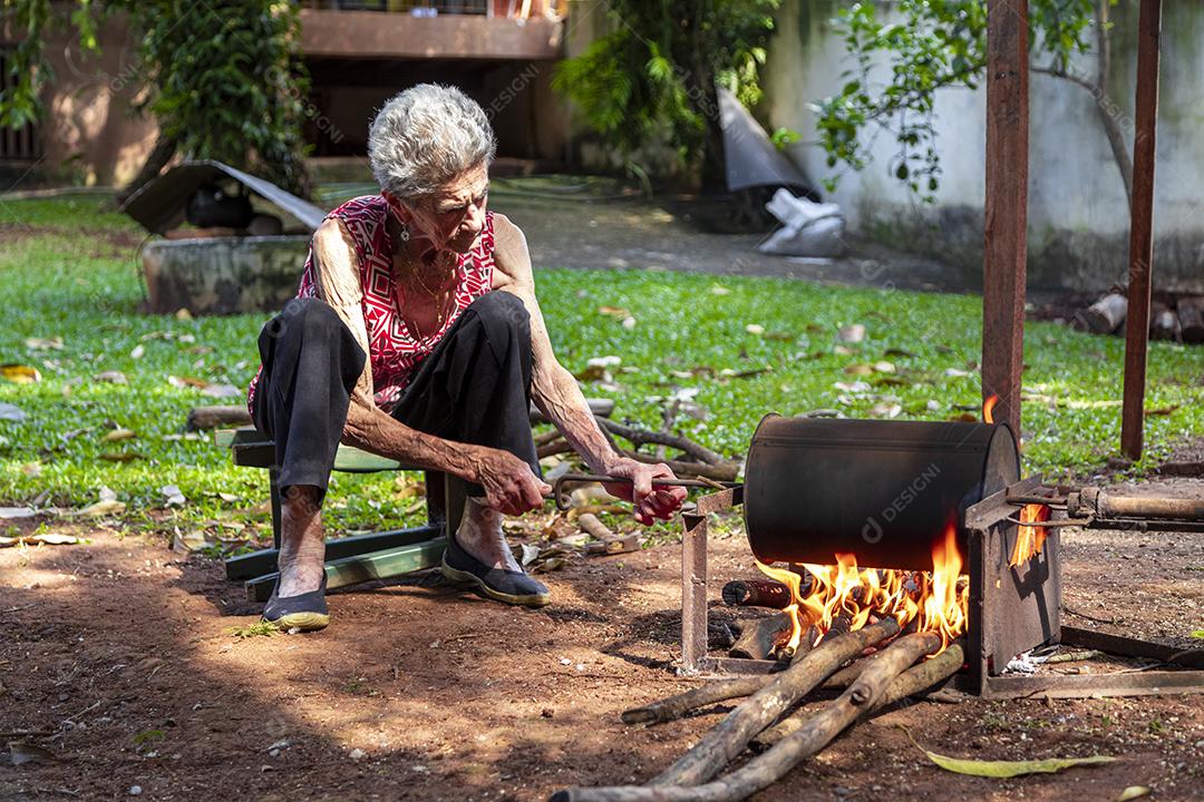 Mulher idosa torrando café manualmente Imagem JPG