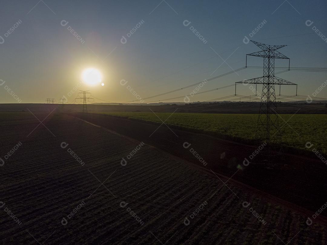 Pôr do sol entre torres de energia Imagem JPG