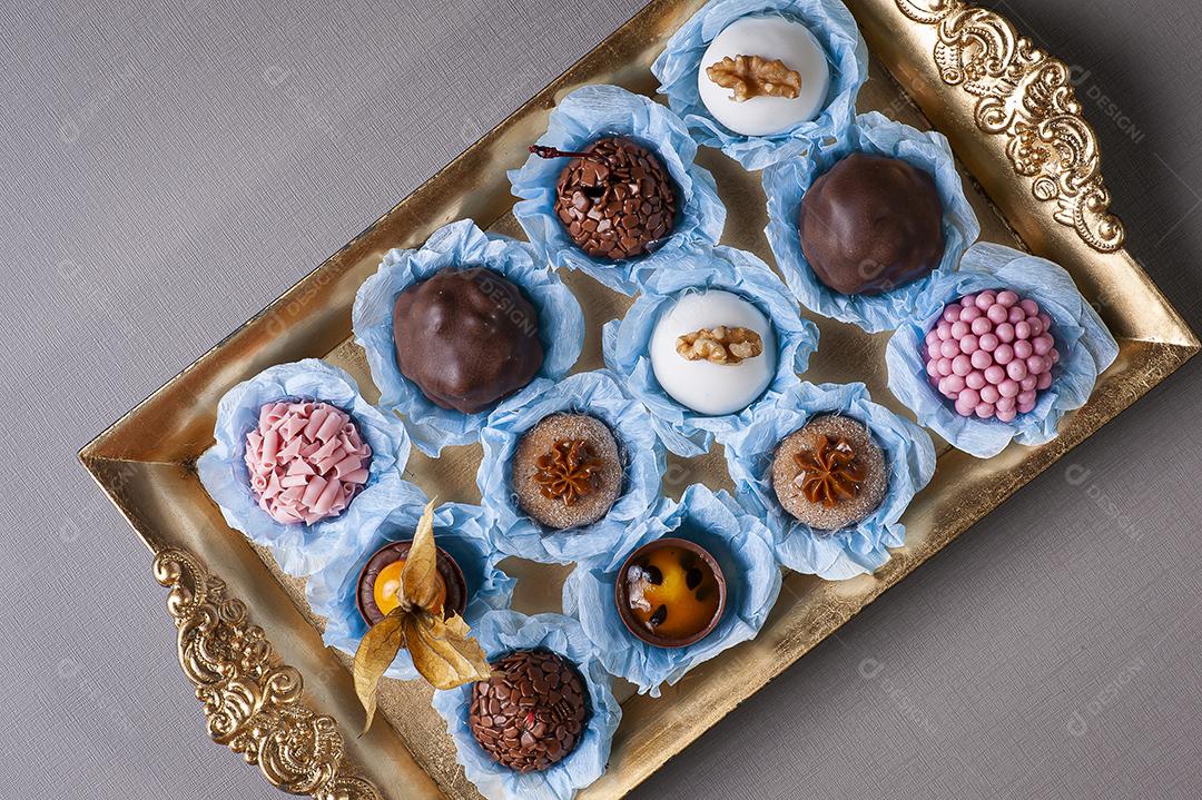 Vários tipos de brigadeiro gourmet em uma bandeja dourada. Doce típico do Brasil com leite condensado e chocolate