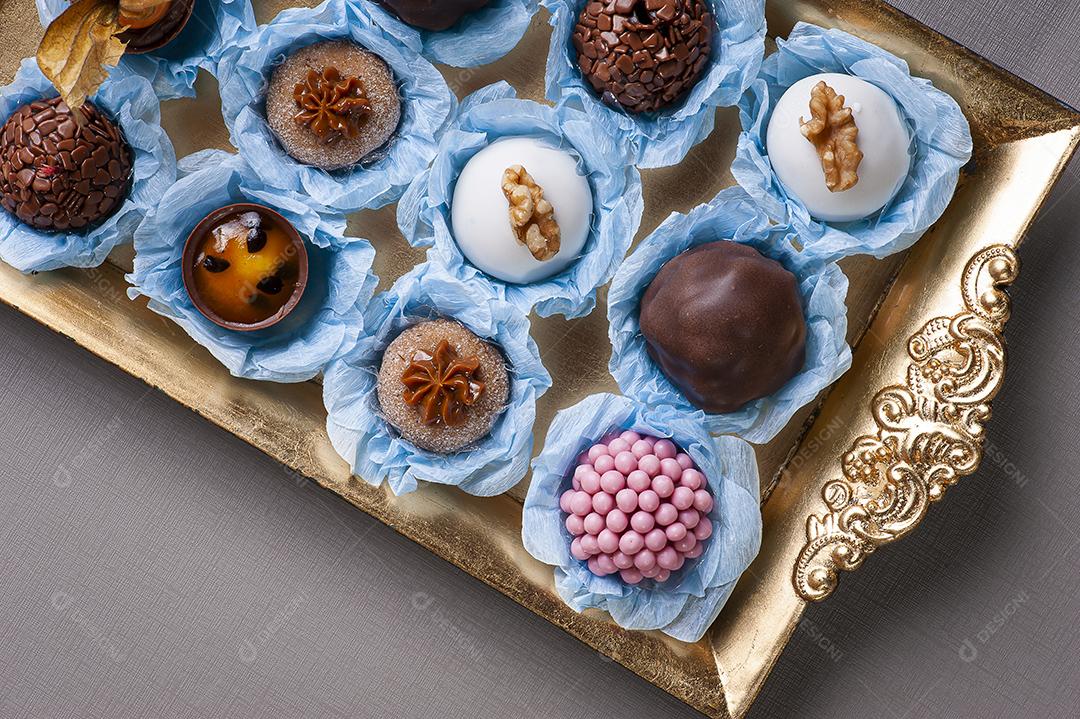 Vários tipos de brigadeiro gourmet em uma bandeja dourada. Doce típico do Brasil com leite condensado e chocolate