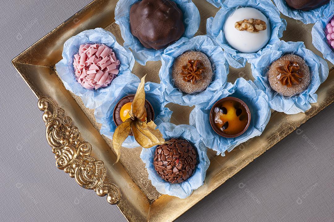 Vários tipos de brigadeiro gourmet em uma bandeja dourada. Doce típico do Brasil com leite condensado e chocolate