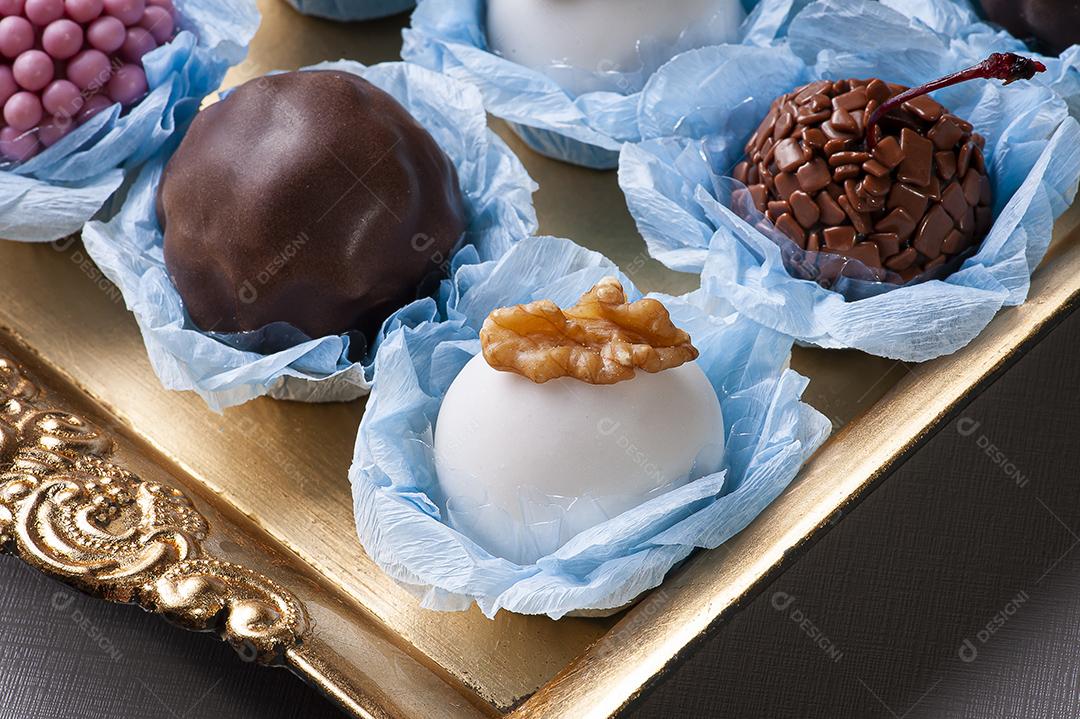 Vários tipos de brigadeiro gourmet em uma bandeja dourada. Doce típico do Brasil com leite condensado e chocolate