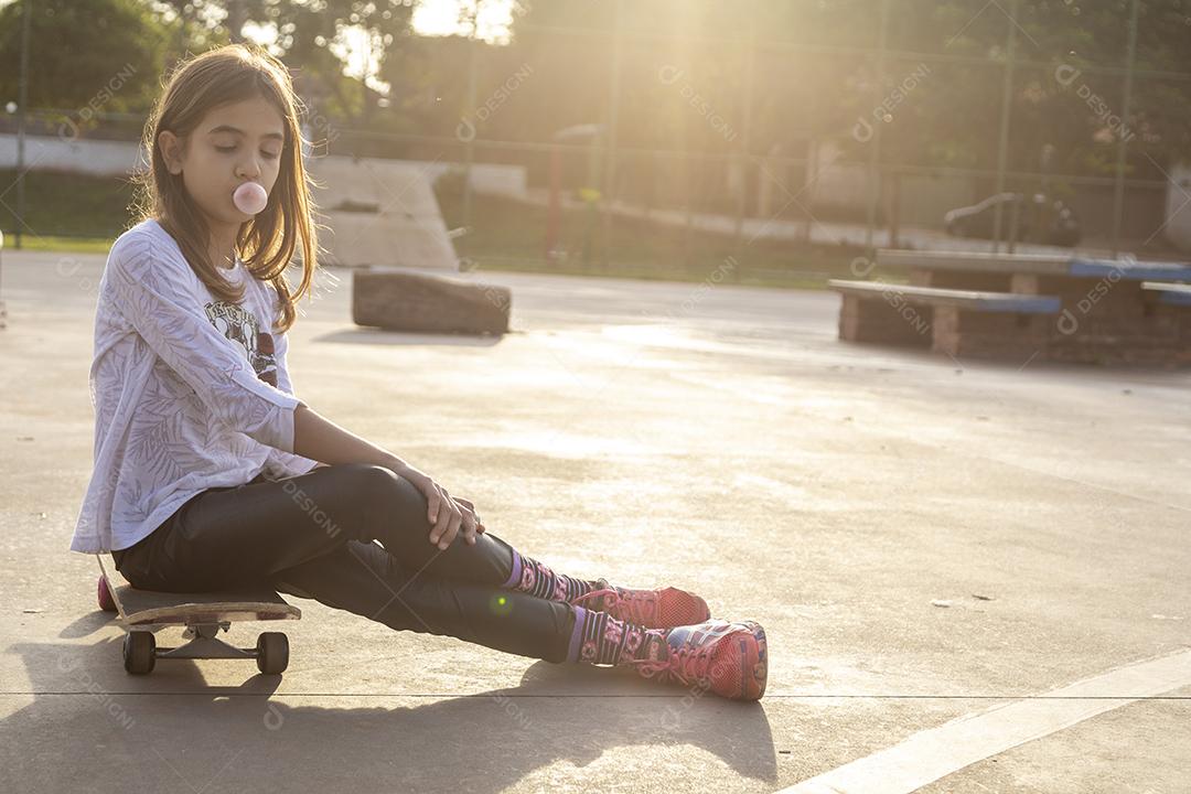 Girl sitting on a skateboard on a court Image JPG