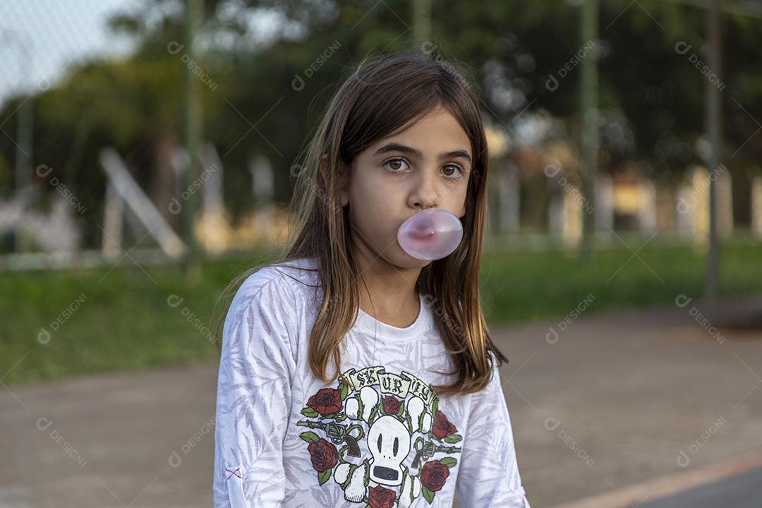 Fotos Garota em uma quadra tirando fotos mascando um chiclete