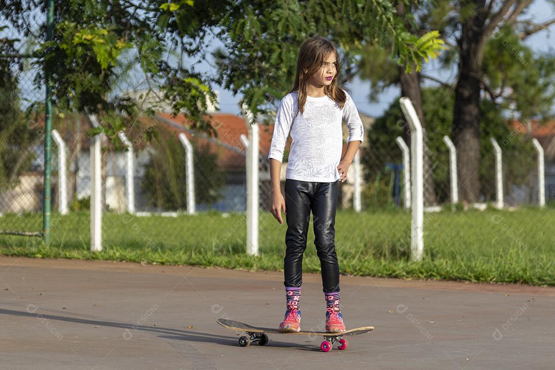 Linda loira andando de skate no parque ao pôr do sol Imagem JPG