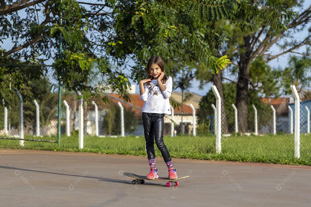 Linda loira andando de skate no parque ao pôr do sol Imagem JPG