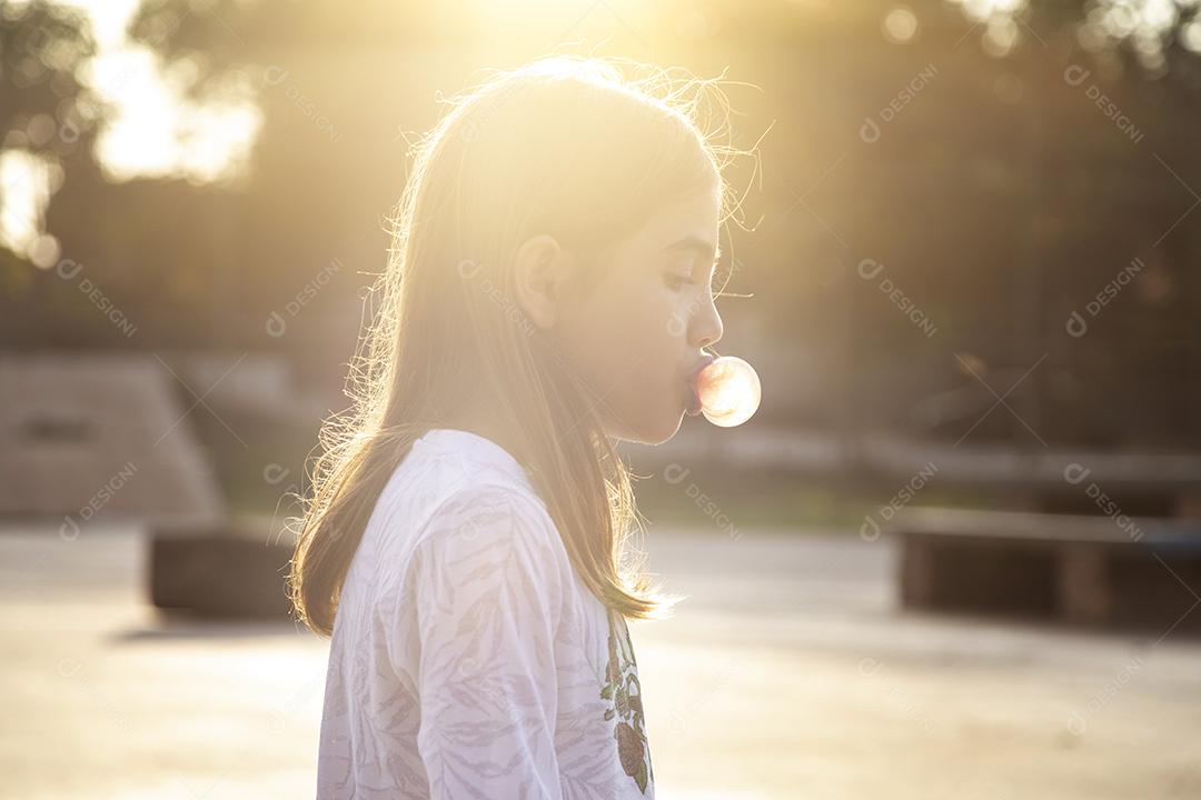 Linda loira sentada em cima do skate no parque ao pôr do sol Imagem JPG