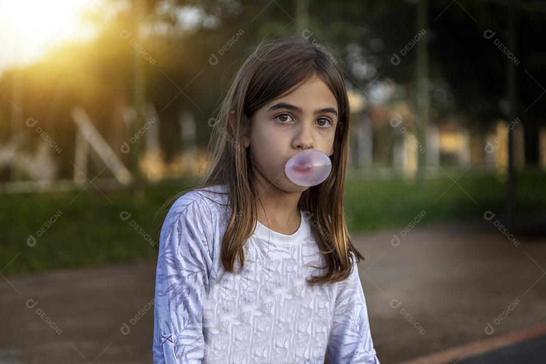 Linda loira sentada em cima do skate no parque ao pôr do sol Imagem JPG