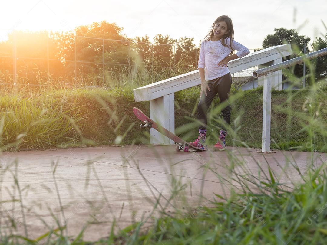 Linda loira andando de skate no parque ao pôr do sol Imagem JPG