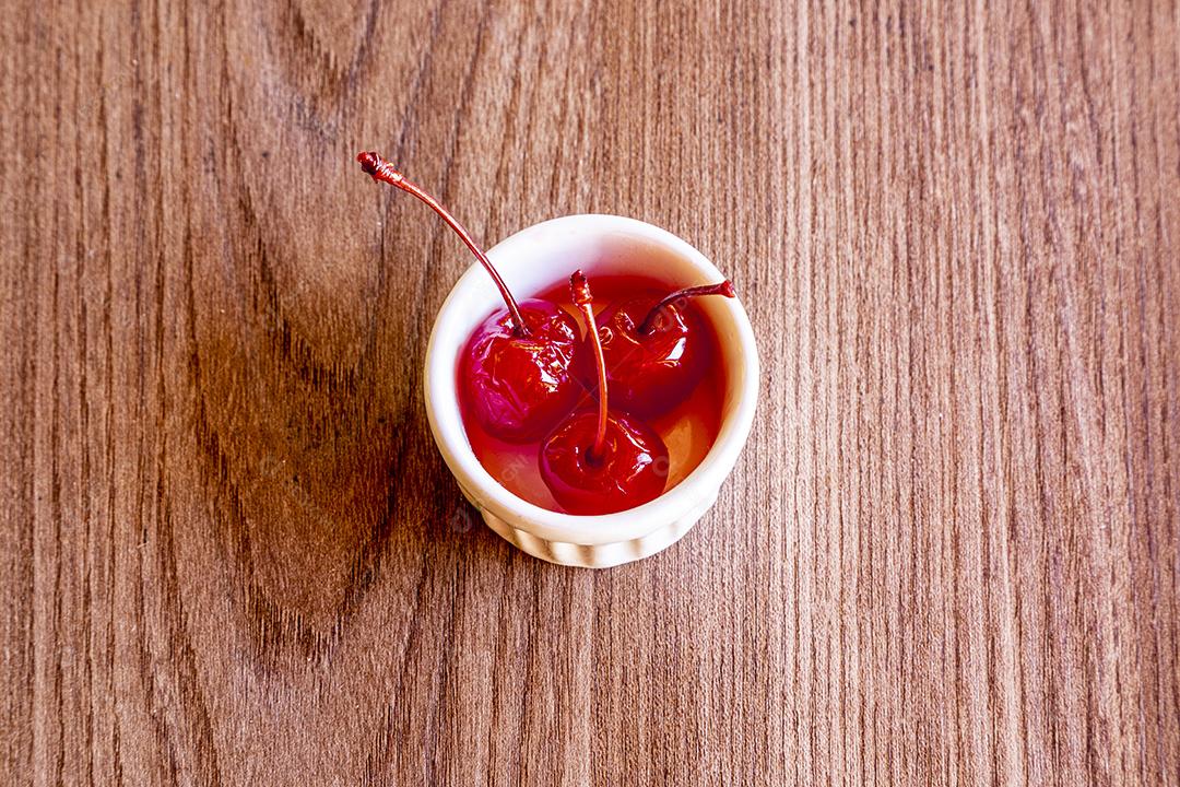 Deliciosas cerejas em tigela sobre fundo de madeira Imagem JPG