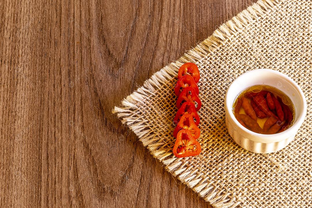 Tigela pequena com óleo e pimenta no fundo de madeira rústica Imagem JPG