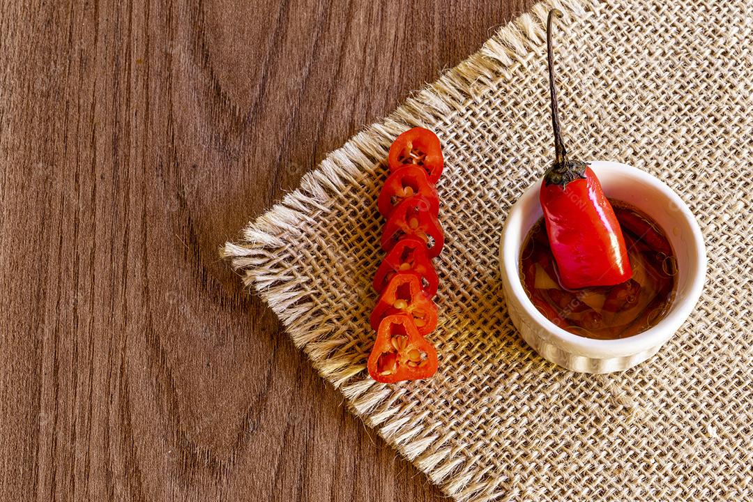 Tigela pequena com óleo e pimenta no fundo de madeira rústica Imagem JPG