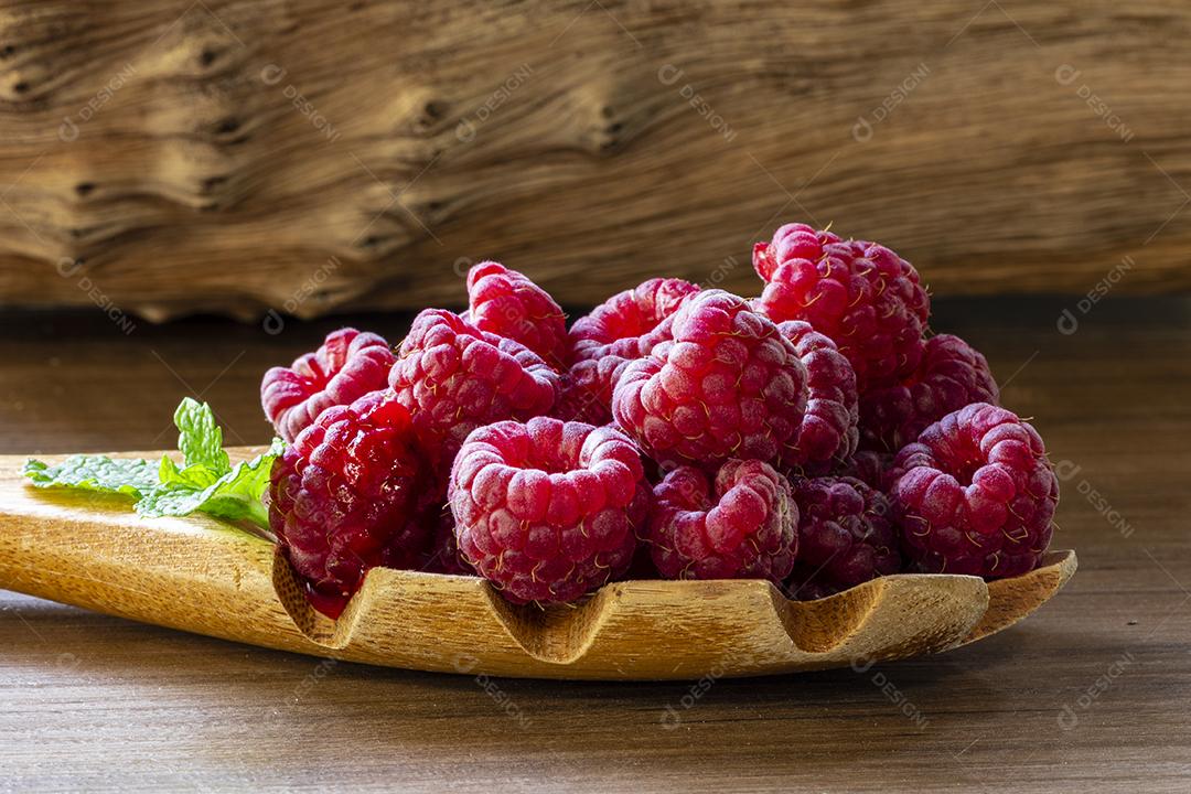 Colher com framboesa e tigela com geléia de framboesa no fundo de madeira Imagem JPG