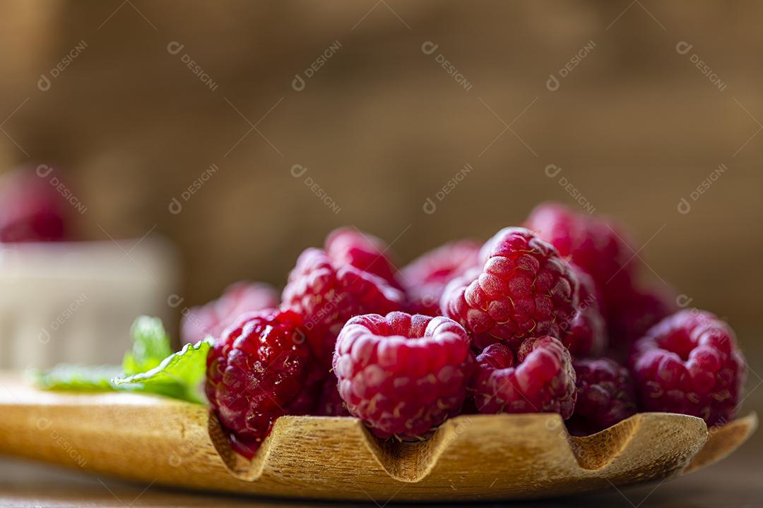 Colher com framboesa e tigela com geléia de framboesa no fundo de madeira Imagem JPG