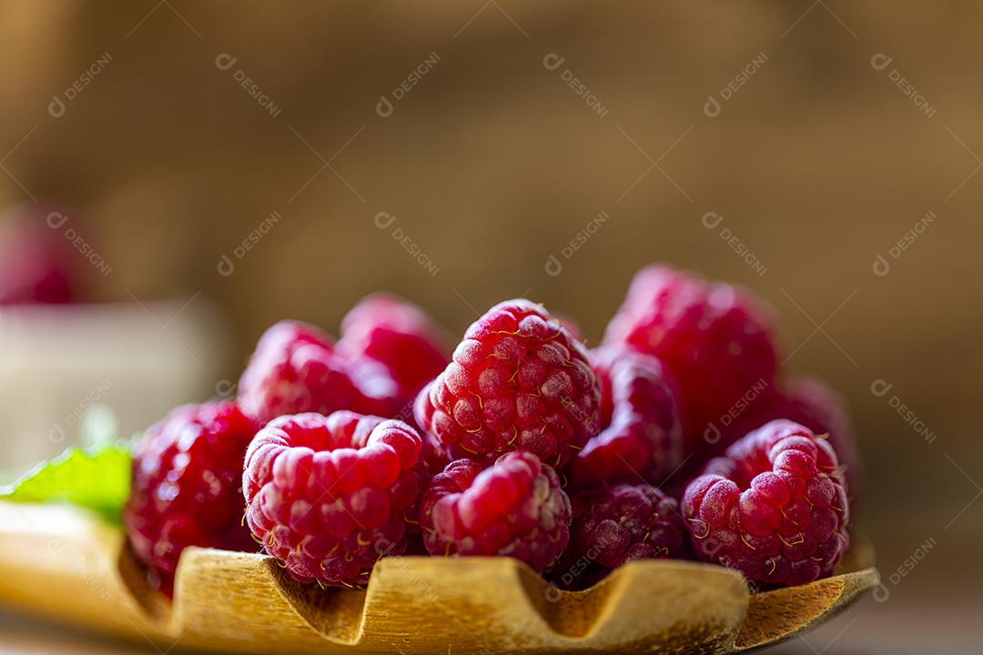 Colher com framboesa e tigela com geléia de framboesa no fundo de madeira Imagem JPG