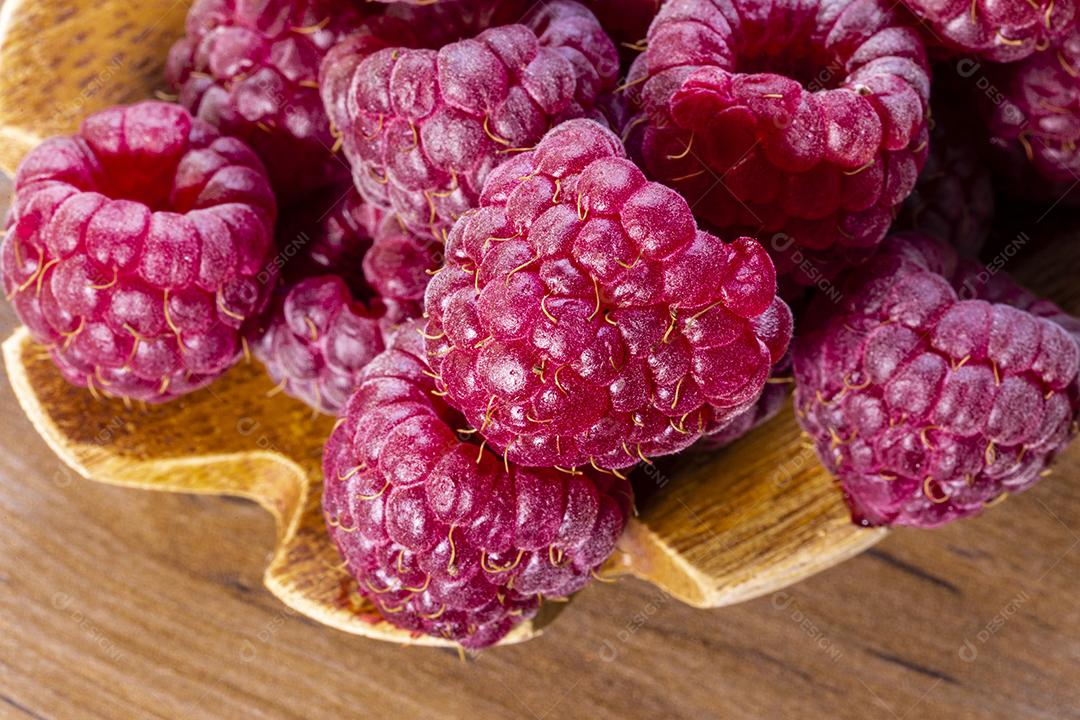 Colher com framboesa e tigela com geléia de framboesa no fundo de madeira Imagem JPG