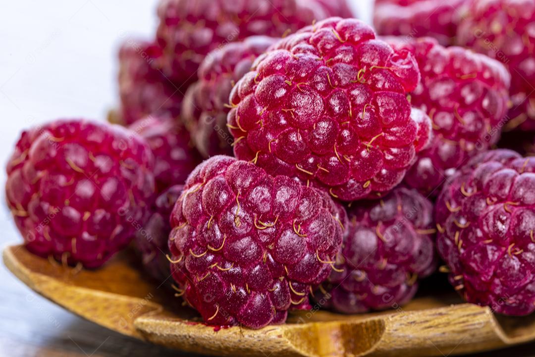 Colher com framboesa e tigela com geléia de framboesa no fundo de madeira Imagem JPG